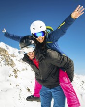 Happy young caucasian skiers couple in love having fun together playing in mountains piggybacking
