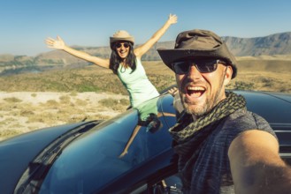 Happy travelers taking selfie photo on summer road trip with rented car in Turkey, symbolizing