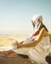 Traveler woman or tourist wear white dress sitting near Great Mosque of Mardin overlooking vast
