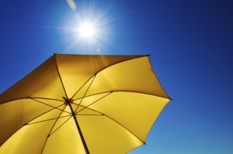 Open Yellow Umbrella with Bright Sun and Blue Sky