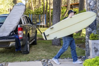 Man carrying a surfboard ready for a surfing adventure
