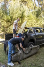 Two men packing surfboards into a truck