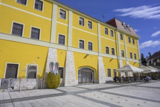 Square in front of old house with café and glittering Easter bunny figure, Varaždinske toplice,