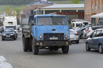 An old blue lorry drives along a busy road, surrounded by other vehicles, Armenia