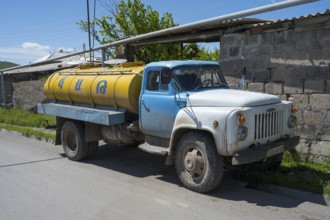 A blue and yellow petrol tanker stands by the roadside in a village, Armenia