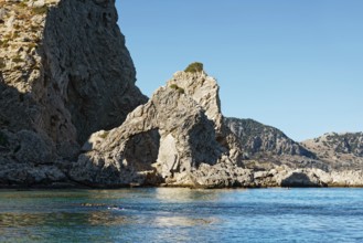 Stone arch at Grande blue beach with clear blue water and sunny sky, showing a natural and peaceful