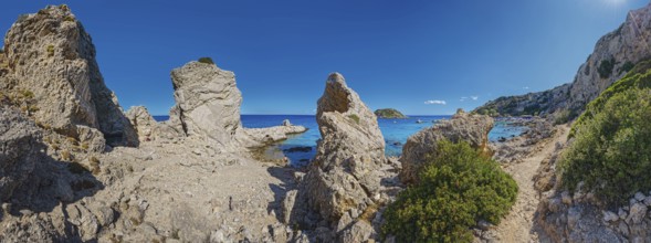 Rocky coastline with panoramic sea view at Grande Blue Beach with small island and clear sky above,