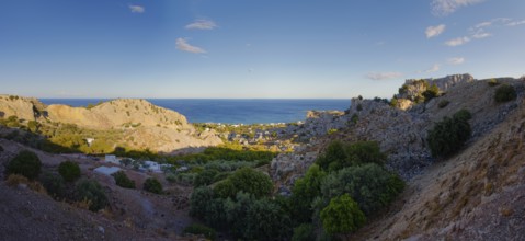 Panoramic view of the hilly coastal landscape of Stegna with clear blue sky and natural vegetation,