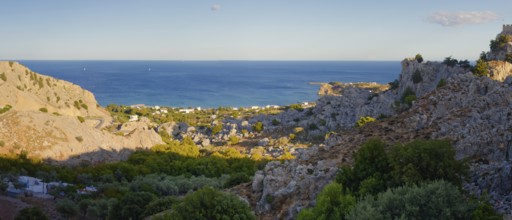 Coastal landscape of Stgna overlooking the sea, framed by rocky hills and lush vegetation, under a