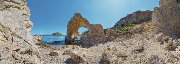 Rocks and rock arches on Grande Blue Beach under a clear blue sky in a sunny coastal landscape,