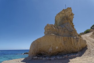 An impressive rock formation on Grande Blue Beach with clear blue sky and sea in the background,