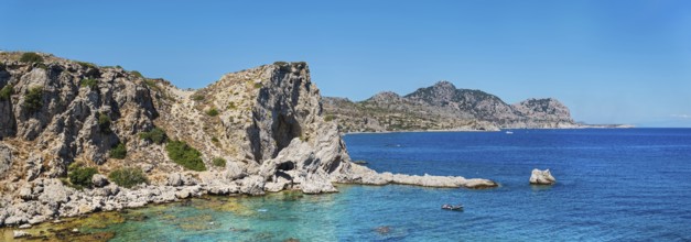 Rocky coastal landscape at Grande Blue Beach with clear blue water and a bright blue sky, Grande
