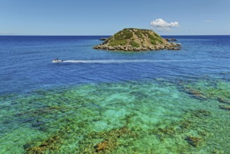 Small island Vrachonisida in front of the Grande Blue Beach in the turquoise blue sea with passing