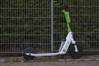 On the side of the road, fence, parked e-scooter, electric scooter, scooter, in the bike rental of