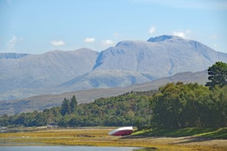 An overturned boat in front of an impressive mountain backdrop in fine weather, view of Ben Nevis,