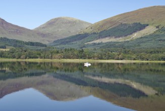 A boat on a glassy loch surrounded by mountains under a clear sky, Loch Eil, Scotland, Great