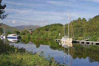 River landscape with boats and wooded hills in the background, Caledonian Canal, Fort William,