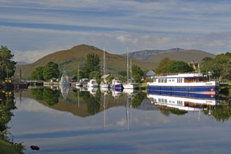 Water reflections of boats in the harbour in front of picturesque mountains, Caledonian Canal,