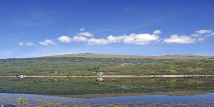A clear lake reflects the surrounding mountains and cloudy sky, Caledonian Canal, Fort William,
