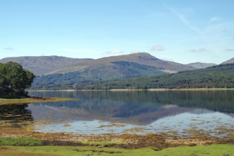 Calm lake with reflections of the surrounding mountains and blue sky, Scotland, Great Britain, Loch