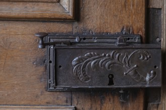 Detail of an old metal lock on a carved wooden door frame, Hesse, Germany