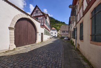 Old town, alley, cobblestone pavement, historic half-timbered houses, wall, access gate, blue sky,