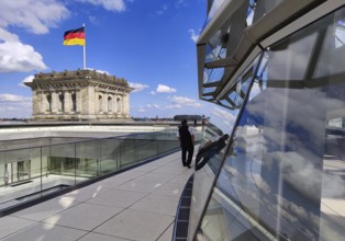 Viewing platform with a German flag in the wind on one of the corner towers and the Reichstag dome,
