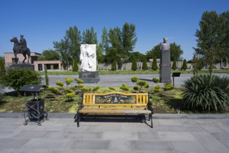 Park with colourful wooden benches, statues and surrounding trees, in the garden of the Yazidi