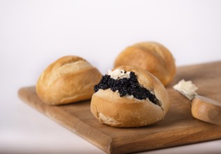 Round wheat buns with butter and black caviar, copy space
