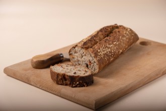 Slices of whole grain bread with carrots and seeds on wooden board on beige background, copy space