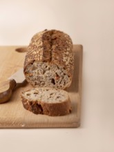 Whole grain bread with carrots and seeds on wooden board on beige background, copy space