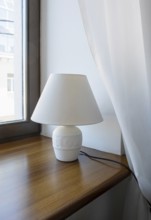 A table lamp, a night light stands on the windowsill in a hotel