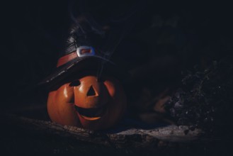 Pumpkin lantern with witch's hat in a spooky, dark setting