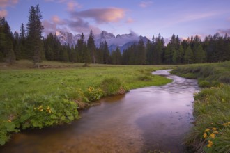 View along the Fiume Ansiei stream over a forest to the Sorapis mountain group in the evening