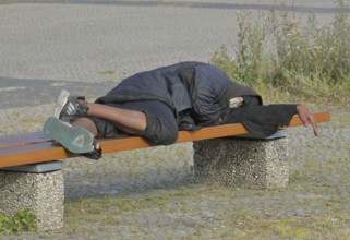 Homeless man sleeping on a bench, Ernst-Reuter-Platz, Charlottenburg, Berlin, Germany ! Personal