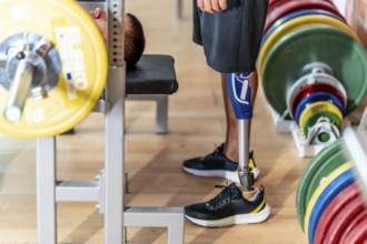 Adaptive athlete with a prosthetic leg doing weightlifting exercises on a gym bench, demonstrating