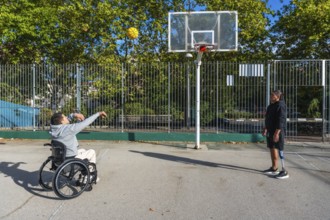Two young men, one using a wheelchair and another with a prosthetic leg, playing basketball on an
