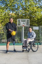 Two men, one with a prosthetic leg holding a basketball and another sitting in a wheelchair,