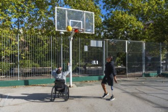 Men with prosthetic leg and wheelchair playing basketball outdoors, demonstrating inclusion,