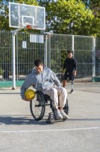 Young men with physical disabilities engaging in adaptive basketball. One person using a wheelchair
