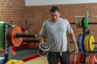 Mature man concentrating on a bicep curl with a dumbbell in a gym, focused on strength training,