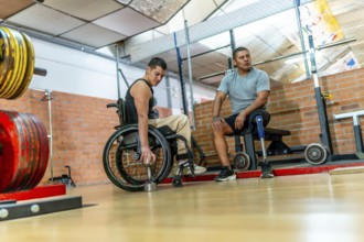 Adaptive athletes with physical disabilities engaging in training at a gym, one man in a wheelchair