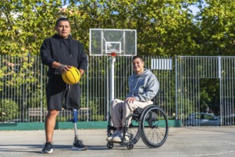 Two young men, one with a prosthetic leg holding a basketball and another sitting in a wheelchair,