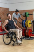 Disabled man in a wheelchair looking cheerful and smiling at the camera while another man with a