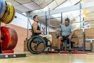 Two men with disabilities training together in a gymone in a wheelchair, one with a prosthetic