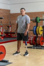 Male amputee athlete standing confidently in a gym, showcasing his prosthetic leg and symbolizing