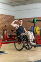 Young man in a wheelchair posing with a flexed bicep, showing determination and strength while