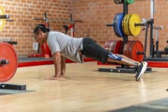Athlete with prosthetic leg doing push ups on a gym floor, showcasing adaptive strength training,