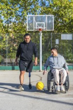 Two friends play basketball on an outdoor court, one man with a prosthetic leg, the other in a
