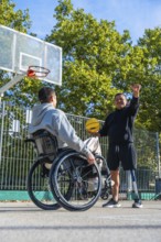 Smiling men with physical disabilities engaging in a friendly game of basketball on an outdoor